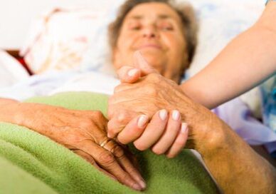 Elderly women in bed holding hand