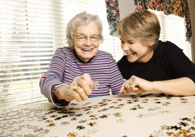 Elderly Woman and Younger Woman Doing Puzzle