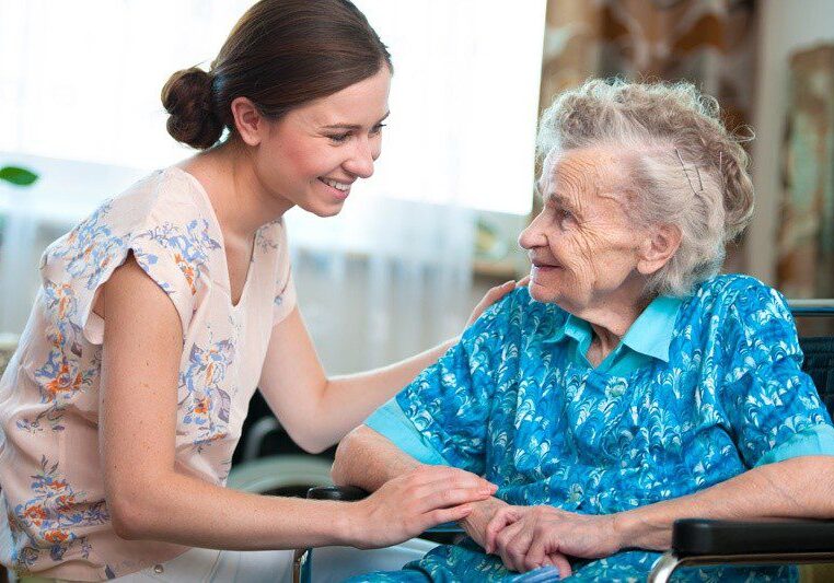 Young Care Worker assisting the elderly - both smiling